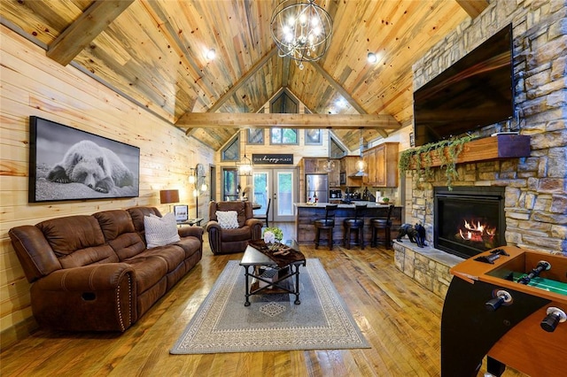 living area with wooden ceiling, light wood finished floors, a stone fireplace, and wood walls