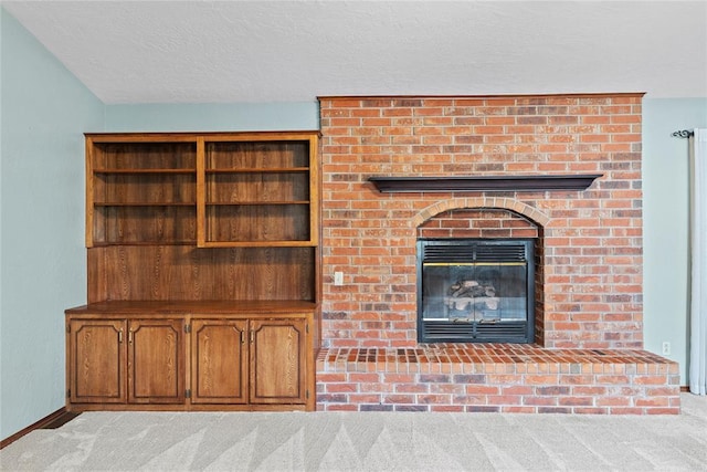 unfurnished living room with light colored carpet, a textured ceiling, and a brick fireplace