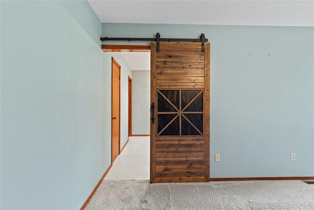 interior space with a barn door and light colored carpet