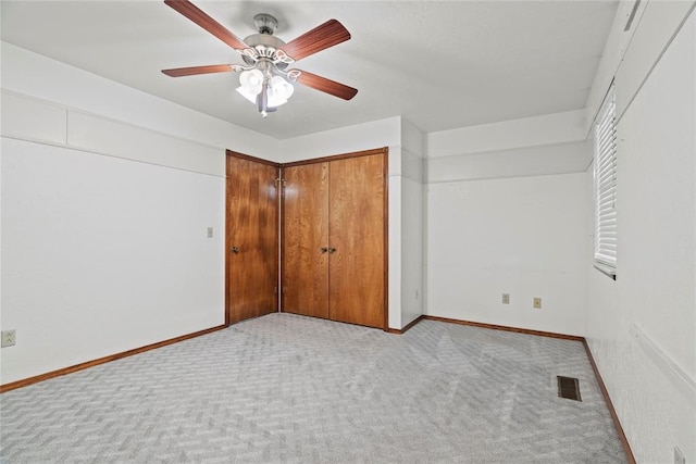 unfurnished bedroom featuring ceiling fan, light colored carpet, and a closet