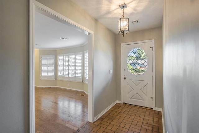 entrance foyer with light hardwood / wood-style flooring, a wealth of natural light, a notable chandelier, and crown molding