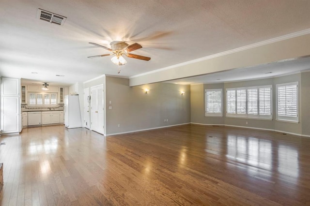 unfurnished living room featuring ceiling fan, hardwood / wood-style floors, a textured ceiling, and ornamental molding