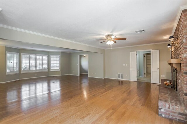 unfurnished living room with ceiling fan, light hardwood / wood-style flooring, ornamental molding, and a brick fireplace