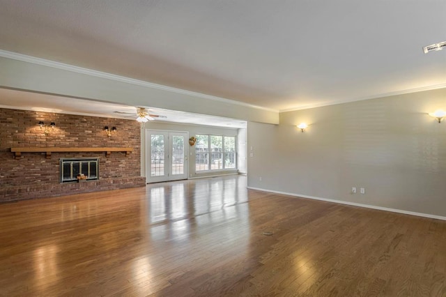 unfurnished living room with hardwood / wood-style floors, french doors, ceiling fan, ornamental molding, and a fireplace