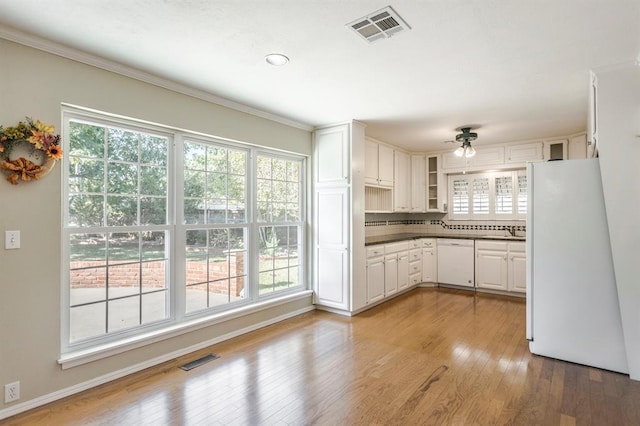 kitchen featuring white cabinetry, a wealth of natural light, white appliances, and light wood-type flooring