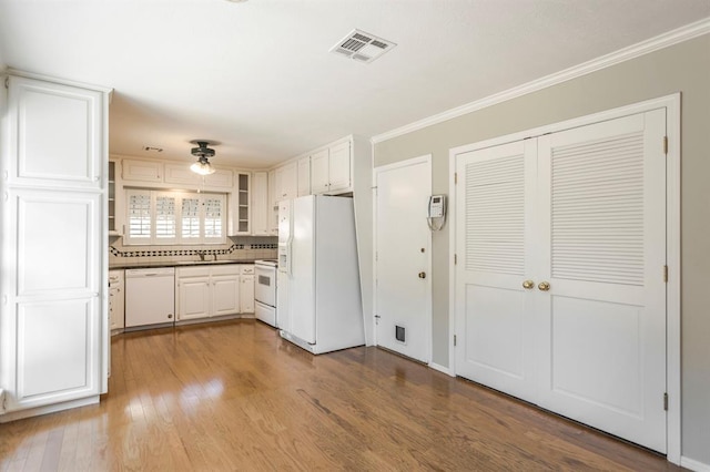 kitchen featuring decorative backsplash, ornamental molding, white appliances, light hardwood / wood-style flooring, and white cabinetry