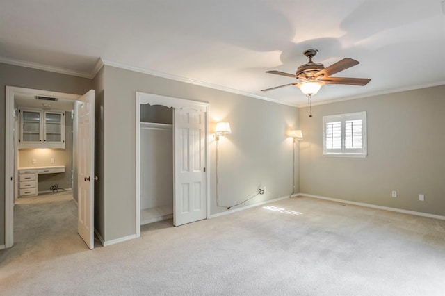 unfurnished bedroom featuring light carpet, built in desk, ceiling fan, and crown molding