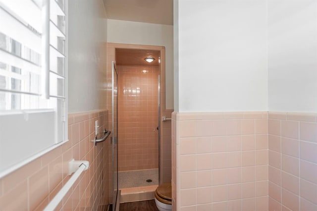 bathroom with toilet, a tile shower, and tile walls