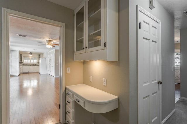 kitchen featuring hardwood / wood-style flooring, ceiling fan, white refrigerator, and white cabinetry