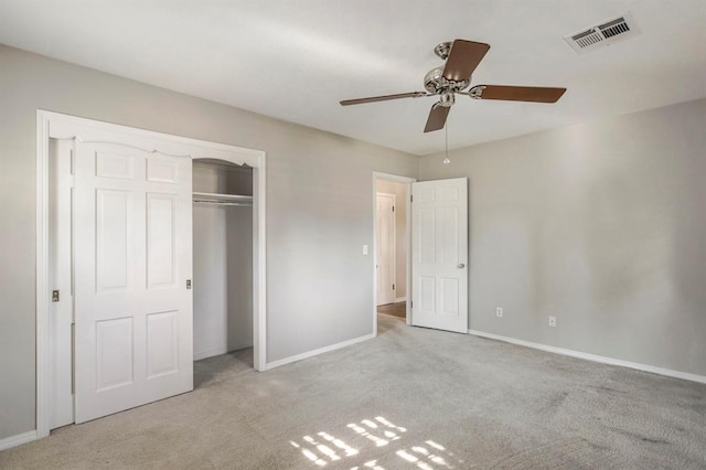 unfurnished bedroom with a closet, light colored carpet, and ceiling fan