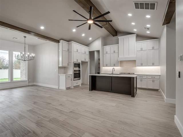 kitchen featuring sink, tasteful backsplash, pendant lighting, a kitchen island with sink, and white cabinets