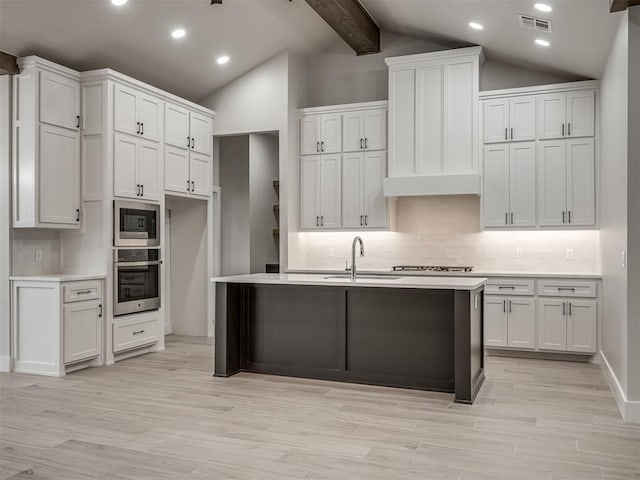 kitchen with tasteful backsplash, white cabinetry, sink, vaulted ceiling with beams, and stainless steel appliances