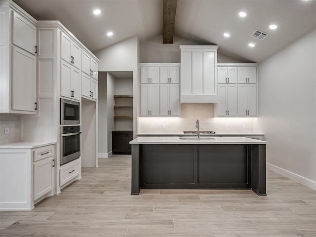 kitchen featuring built in microwave, stainless steel oven, sink, and white cabinets