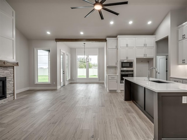 kitchen featuring a fireplace, built in microwave, sink, white cabinets, and stainless steel oven