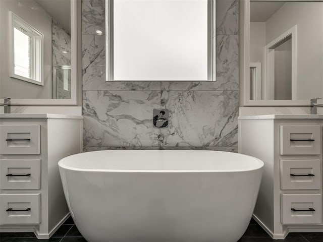 bathroom with tile patterned flooring, vanity, a washtub, and tile walls