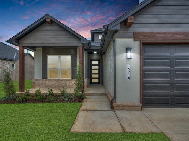 exterior entry at dusk with a garage and a lawn