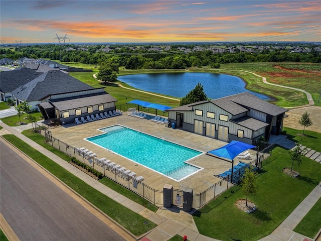 pool at dusk featuring a water view and a patio area