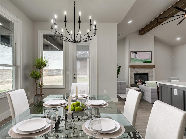 dining area featuring vaulted ceiling with beams, a stone fireplace, and wood-type flooring