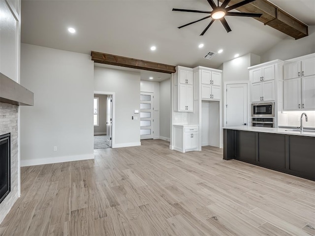 kitchen featuring built in microwave, white cabinetry, a fireplace, and oven