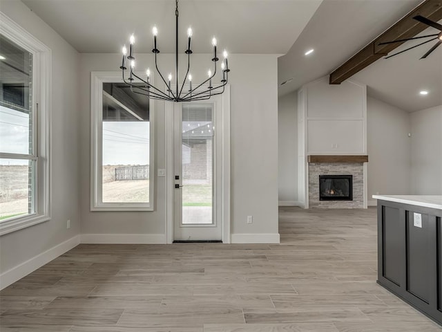 unfurnished dining area with lofted ceiling with beams, a healthy amount of sunlight, a fireplace, and light wood-type flooring