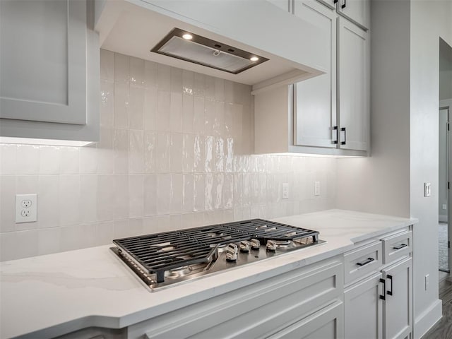 kitchen with tasteful backsplash, light stone countertops, and stainless steel gas cooktop