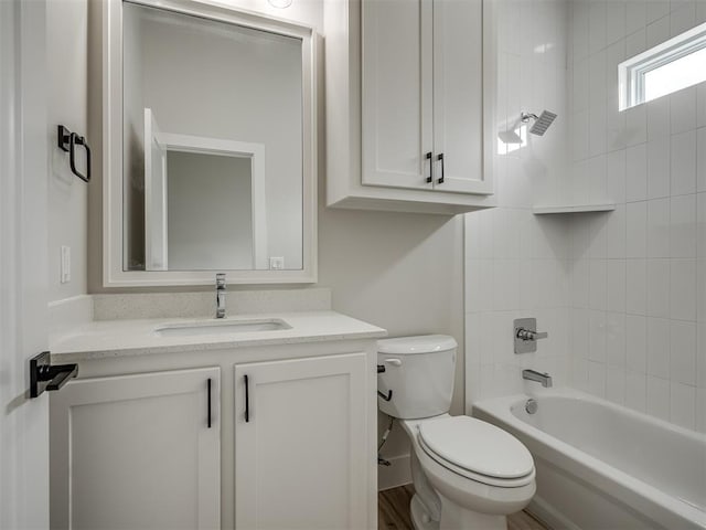 full bathroom featuring vanity, tiled shower / bath combo, and toilet