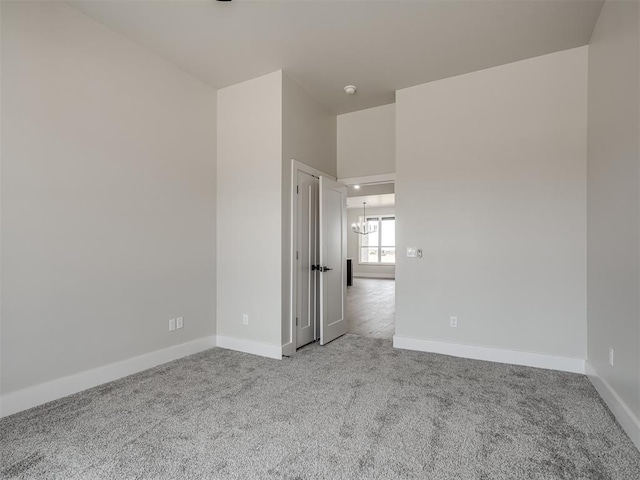 carpeted spare room with a notable chandelier