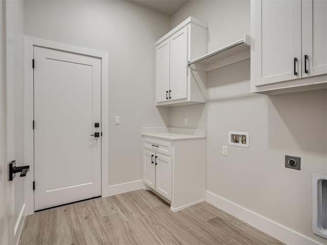 clothes washing area featuring electric dryer hookup, washer hookup, light hardwood / wood-style floors, and cabinets