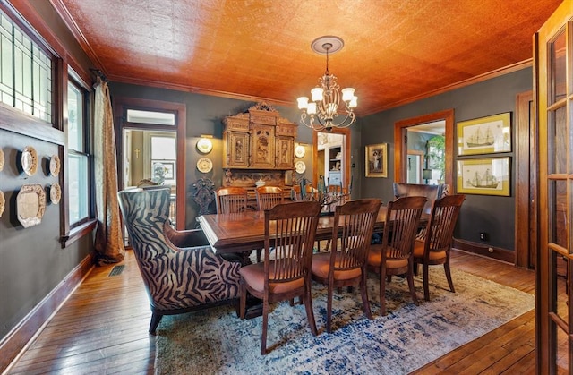 dining area with a healthy amount of sunlight, ornamental molding, dark wood-type flooring, and a chandelier