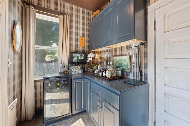 bar with blue cabinetry and beverage cooler