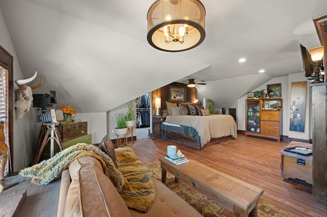 bedroom with lofted ceiling, wood-type flooring, and an inviting chandelier