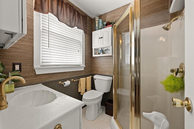 bathroom with tile patterned floors, vanity, toilet, a shower with shower door, and wood walls