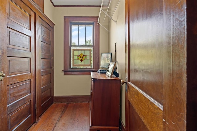 doorway with hardwood / wood-style floors and ornamental molding