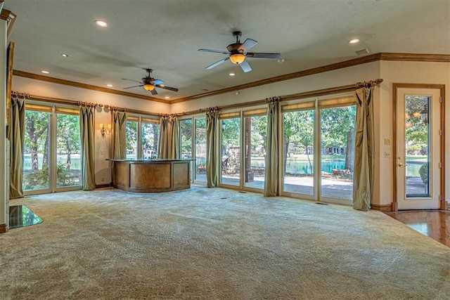 unfurnished living room featuring ceiling fan, ornamental molding, and light carpet