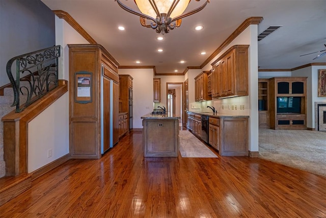 kitchen featuring built in appliances, crown molding, dark wood-type flooring, and a tile fireplace