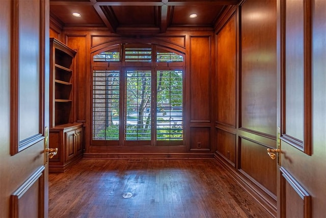 empty room with dark wood-type flooring, beamed ceiling, a healthy amount of sunlight, and coffered ceiling