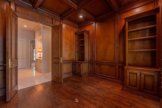 empty room featuring ornamental molding, wood walls, dark wood-type flooring, and coffered ceiling