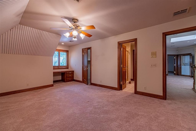 bonus room with built in desk, light colored carpet, ceiling fan, and lofted ceiling