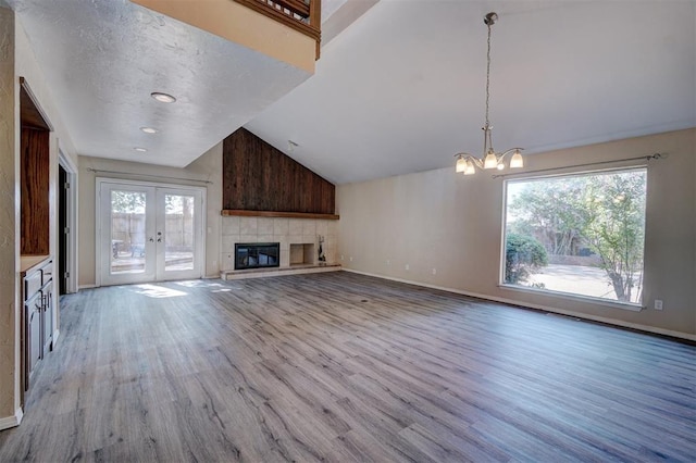 unfurnished living room with a chandelier, french doors, light hardwood / wood-style floors, and high vaulted ceiling