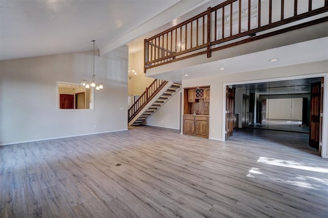 unfurnished living room featuring beamed ceiling, hardwood / wood-style flooring, high vaulted ceiling, and a notable chandelier