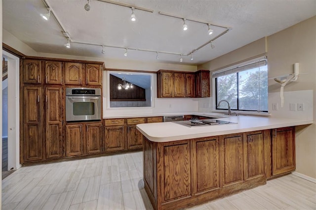 kitchen with kitchen peninsula, appliances with stainless steel finishes, rail lighting, and sink