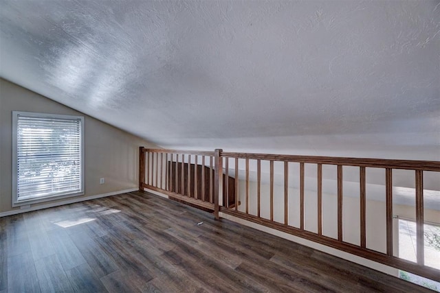 bonus room with a textured ceiling, lofted ceiling, and dark wood-type flooring