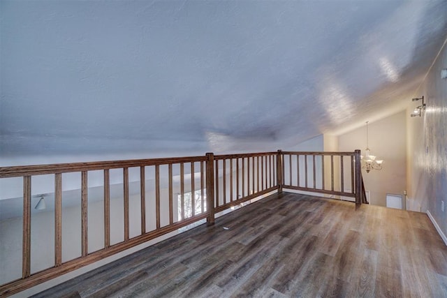 bonus room featuring dark hardwood / wood-style floors, lofted ceiling, and a chandelier