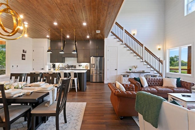 dining area with dark hardwood / wood-style flooring, wooden walls, an inviting chandelier, wooden ceiling, and a high ceiling