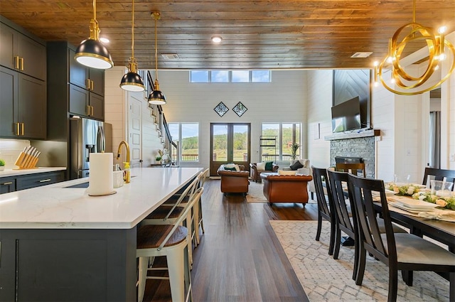 kitchen featuring decorative light fixtures, stainless steel fridge, wooden ceiling, and a towering ceiling