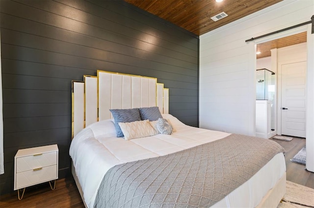 bedroom featuring a barn door, wooden walls, dark wood-type flooring, and wooden ceiling