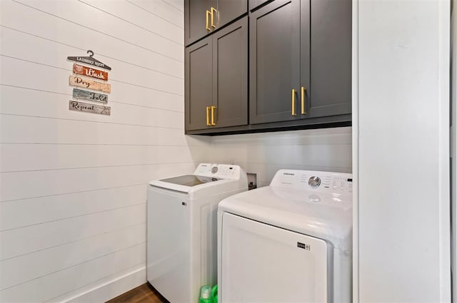 washroom with washer and dryer, cabinets, and wooden walls