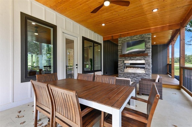 sunroom / solarium with a wealth of natural light, ceiling fan, wooden ceiling, and an outdoor stone fireplace