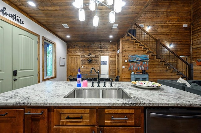 kitchen with wooden walls, light stone counters, wooden ceiling, and sink