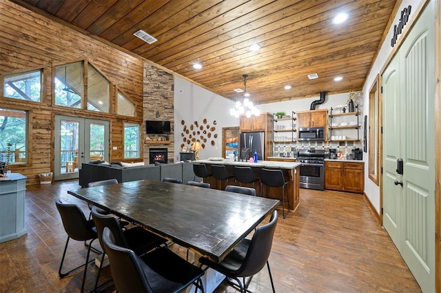 dining room with high vaulted ceiling, wood walls, a fireplace, wood ceiling, and hardwood / wood-style flooring